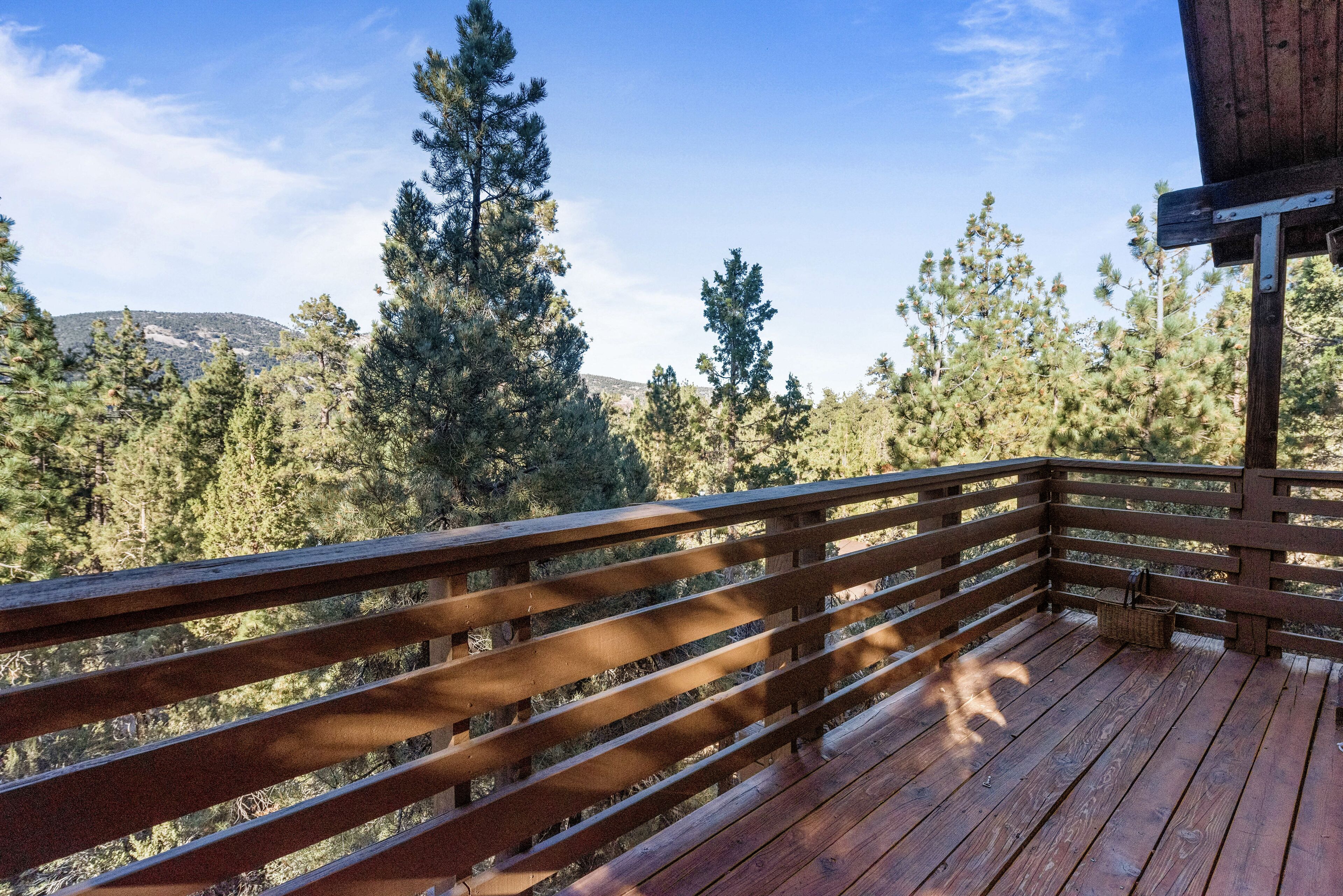 A wooden deck with a view of a forest and distant hills.