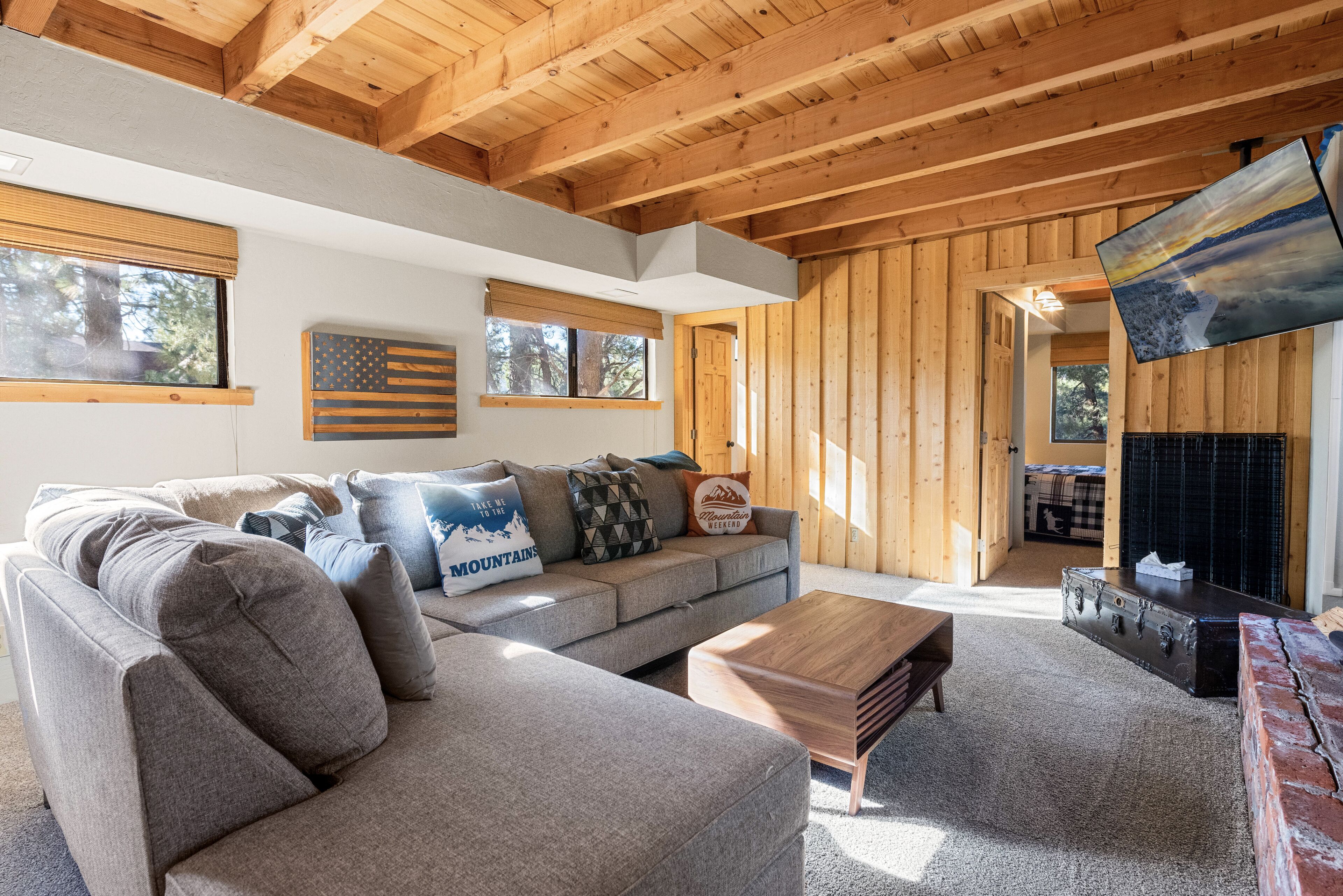 A cozy living room with a sectional sofa, a wooden coffee table, and a fireplace.