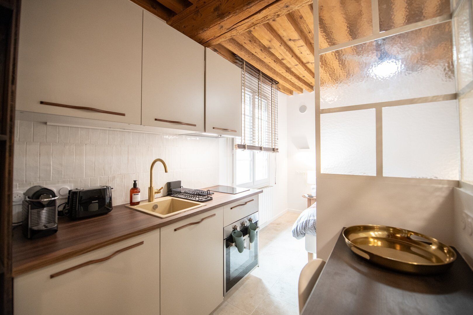 A modern kitchen with white cabinets, a wooden countertop, a sink, a stove, and a window with blinds.