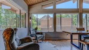 A room with large windows, a dining table, and two chairs.