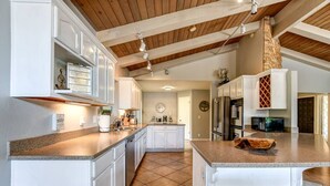 A spacious kitchen with white cabinetry, a central island, and a stone backsplash.