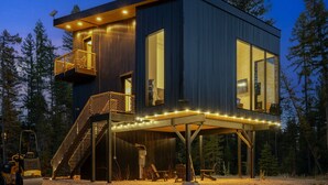 A modern cabin with a deck, large windows, and a staircase. - Off Grid Stays - Treehouse #3 (Columbia Falls)