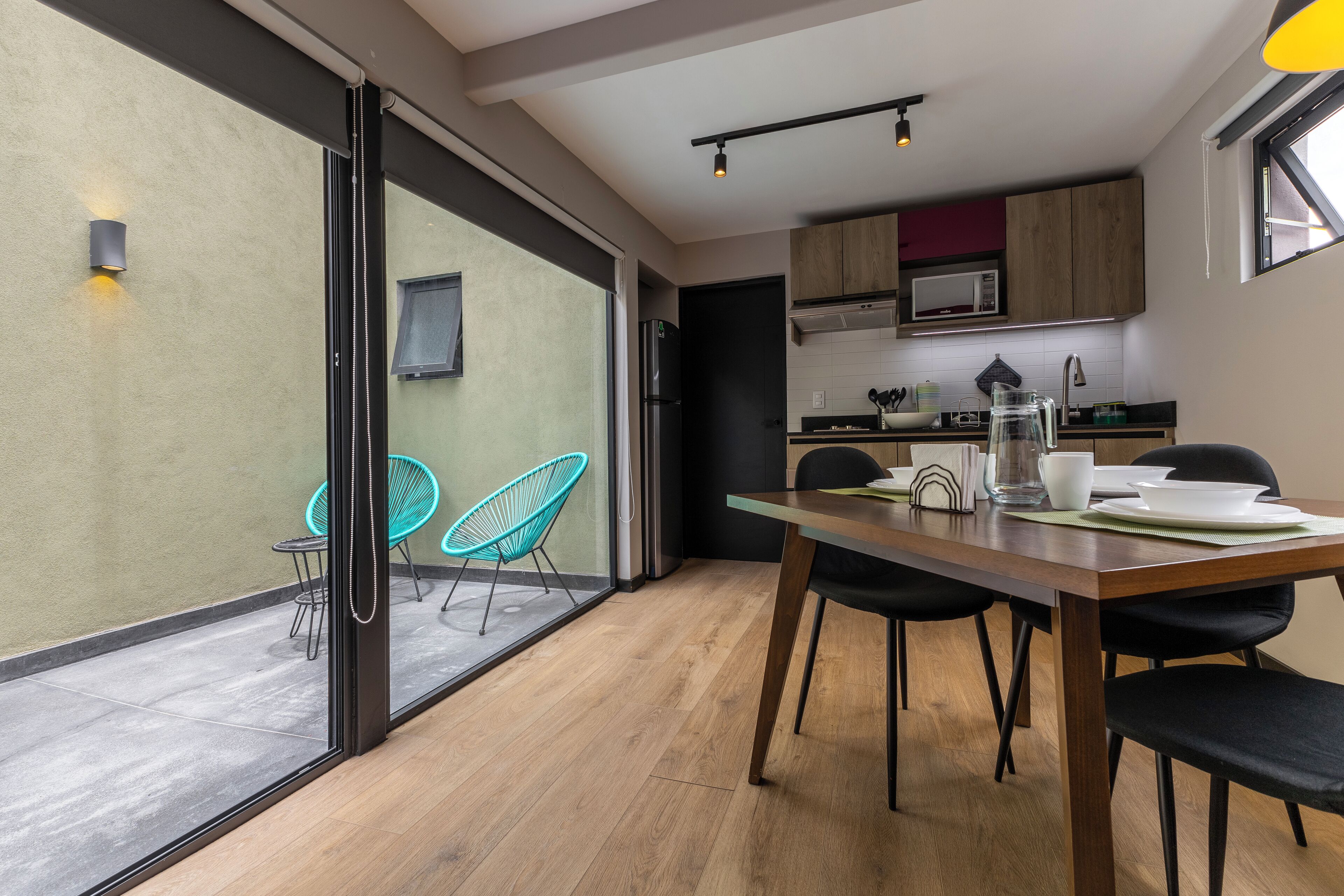A modern kitchen with wooden cabinets, a microwave, and a black refrigerator.