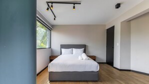 Ein modernes Schlafzimmer mit einem großen Bett, einem Fenster und einer Deckenleuchte.