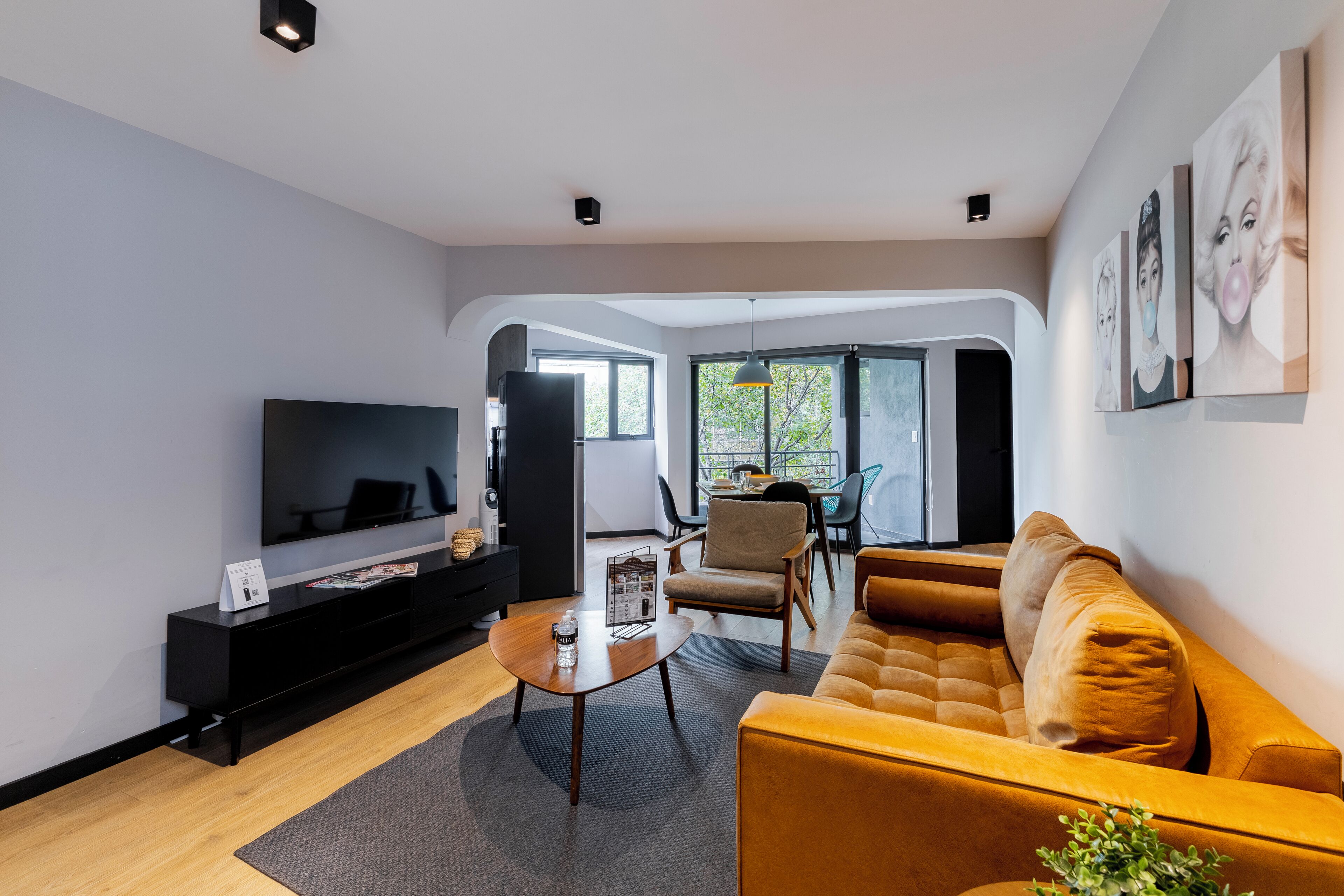 Ein modernes Wohnzimmer mit Flachbildfernseher, einer Couch, einem Couchtisch und einem Essbereich mit Stühlen und Tisch.