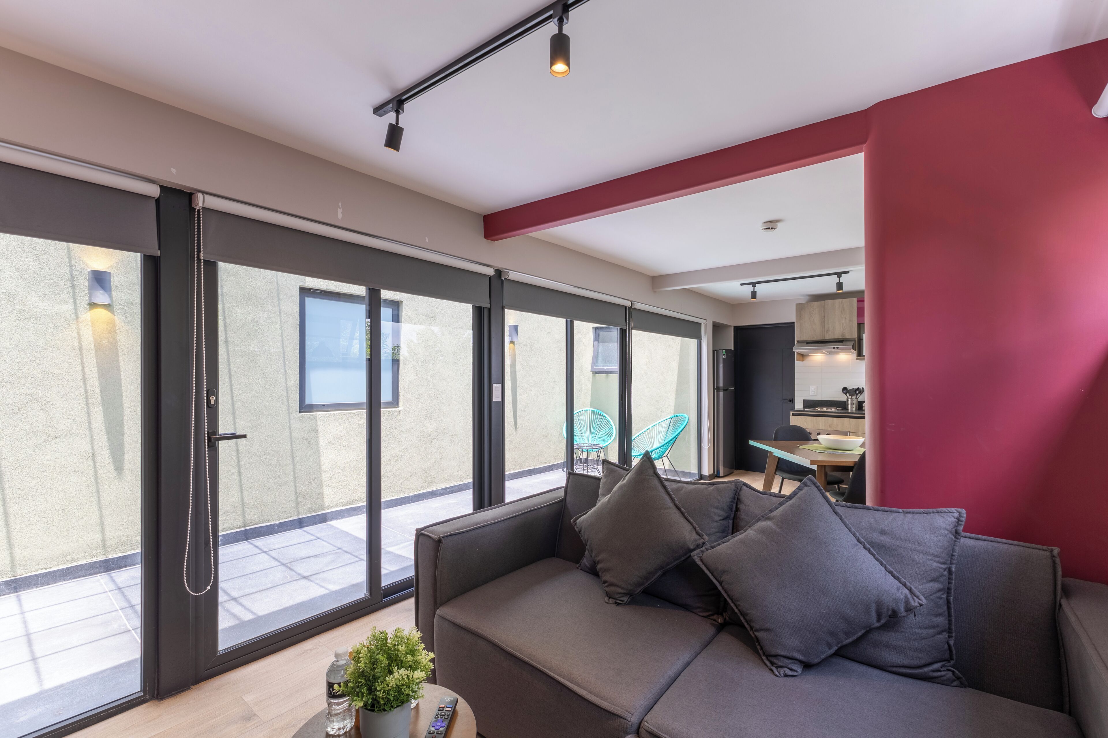 A modern living room with a sofa, a remote control, and a potted plant.