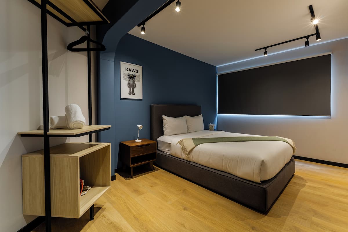 A modern bedroom with a bed, bedside table, and a wall-mounted shelf.