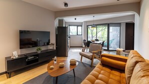 Ein modernes Wohnzimmer mit einer Couch, einem Couchtisch und einem Fernseher auf einer schwarzen Unterhaltungseinheit.