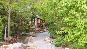 A stone pathway leading to a rustic building surrounded by greenery. - Gorgeous cozy cottage besides a bustling stream, surrounded by gorgeous greenery (Orangeville)