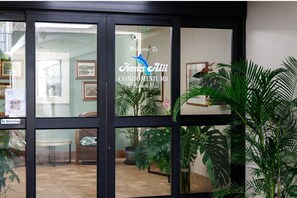Entrada con puerta de vidrio a una propiedad, con un letrero que dice "Welcome to Kona Ali Condominiums El Camino Mai".