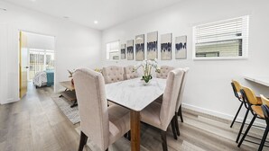 Un espace repas agrémenté d’une table en marbre, de chaises rembourrées et d’œuvres d’art aux murs.