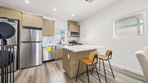 Une cuisine moderne dotée d’appareils électroménagers en acier inoxydable, de meubles en bois et d’un îlot central agrémenté de tabourets de bar.