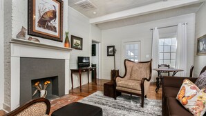Een ruime woonkamer met een open haard, een sofa met luipaardprint en een bijpassende fauteuil.