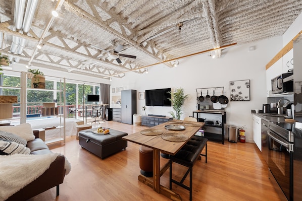 A spacious living area with a wooden dining table, a sofa, and a kitchen with modern appliances. - Mount Pleasant Work & Live Loft (Vancouver)
