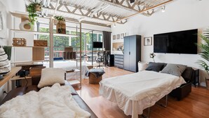 Quarto moderno com uma cama grande, uma cama menor, uma escrivaninha e uma cadeira. Há uma janela com vista para o verde lá fora.