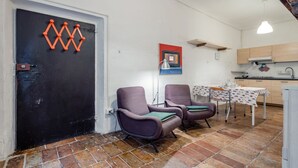 Ein Zimmer mit zwei Stühlen, einem Tisch, einer schwarzen Tür und einer Küchenzeile.