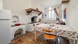 Eine Küche mit einem weißen Kühlschrank, einem Tisch mit Tischtuch mit Fischmuster und einer roten Schüssel auf der Arbeitsfläche.