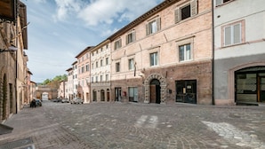 Eine Kopfsteinpflasterstraße gesäumt von historischen Gebäuden, mit verzierten Rundbögen und traditionellen Backsteinfassaden.