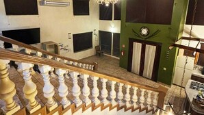 Tilava sisätila, jossa on korkea puinen kattorakenne, valkoisilla kaiteilla varustetut portaat ja koristeellinen kattokruunu.