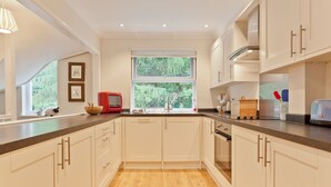 A modern kitchen with light-colored cabinets, a wooden floor, and a window providing a view of greenery. - Herdwick Place, spacious cottage for 4 in spectacular Langdale Valley (Great Langdale)