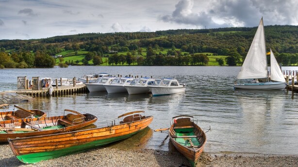 A lakeside dock with several boats, including a sailboat and rowboats, and a wooden pier extending into the water. - Low How Cottage, Coniston, spacious single level, 4 bedroom cottage sleeping 10 (Coniston)