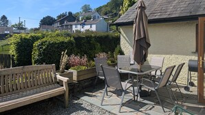 An outdoor patio with a wooden bench, metal chairs, a table, and an umbrella. - Low How Cottage, Coniston, spacious single level, 4 bedroom cottage sleeping 10 (Coniston)