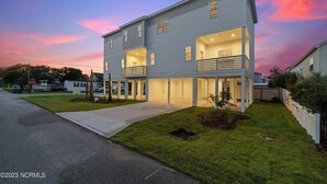 A two-story residential building with a balcony on the second floor, a covered front porch, and a well-maintained lawn. - ‘B’ by the Sea: comfort and style, essentials included! (Carolina Beach)