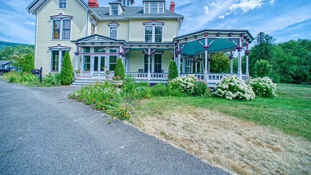 A large, two-story house with a wrap-around porch and a conservatory. - 1930s Cape Cod Bungalow at Firmstone Manor (Clifton Forge)