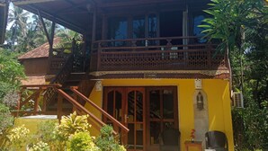 Um edifício de dois andares com varanda, guarda-corpos de madeira e telhado de telhas.