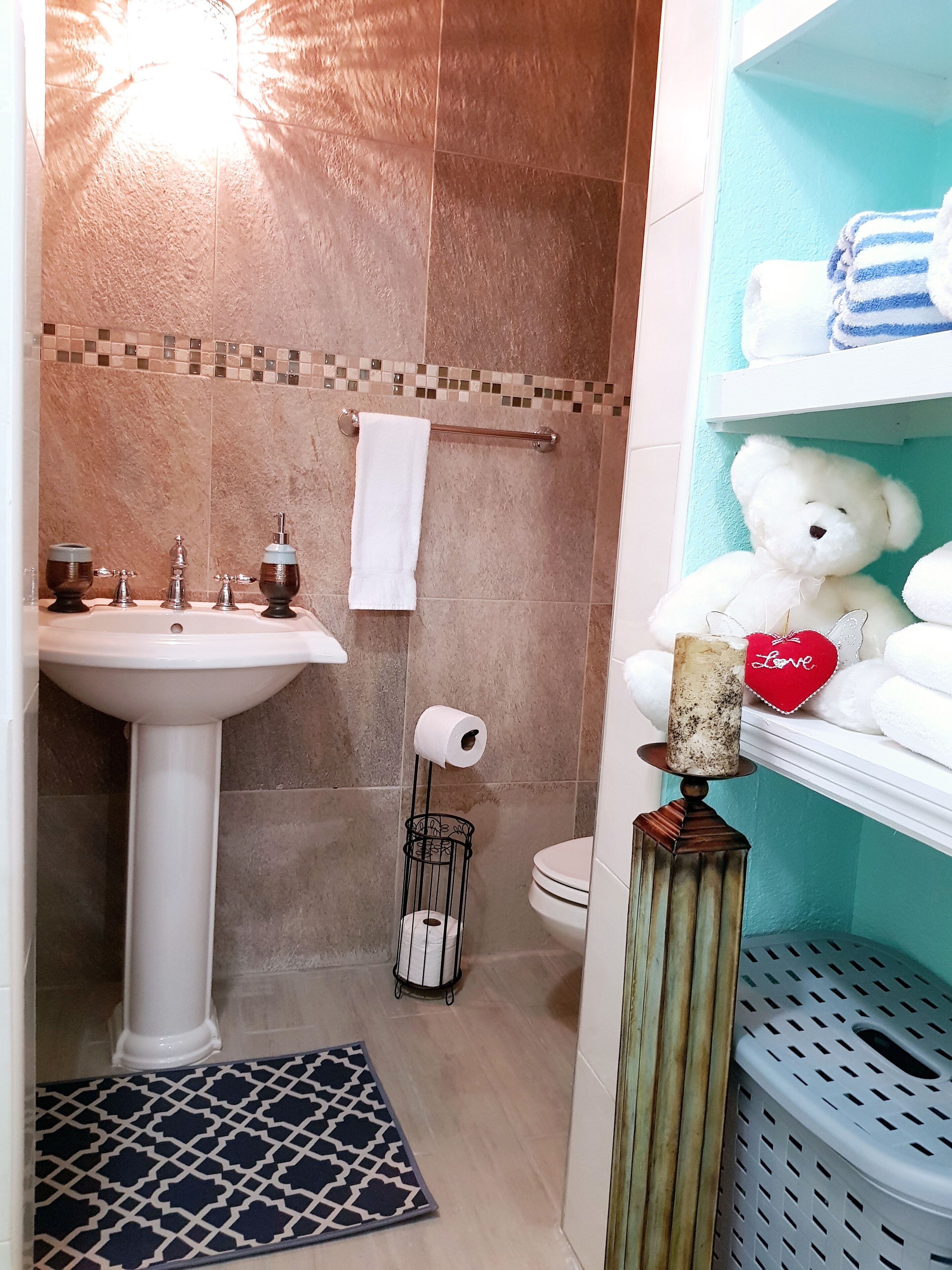 A bathroom with a pedestal sink, a toilet, and a towel rack.