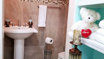 Ein Badezimmer mit einem Waschbecken auf Säule, einer Toilette und einem Handtuchhalter.