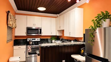 A modern kitchen with white cabinets, a stainless steel refrigerator, and a microwave.