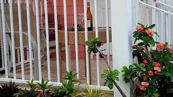 A porch with a white railing, potted plants, and a door.