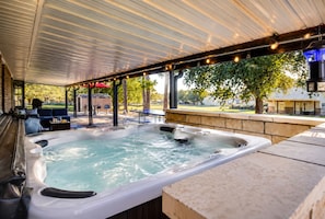 Un espace extérieur abrité avec un jacuzzi, des siÚges, un barbecue et une vue sur un quartier résidentiel.
