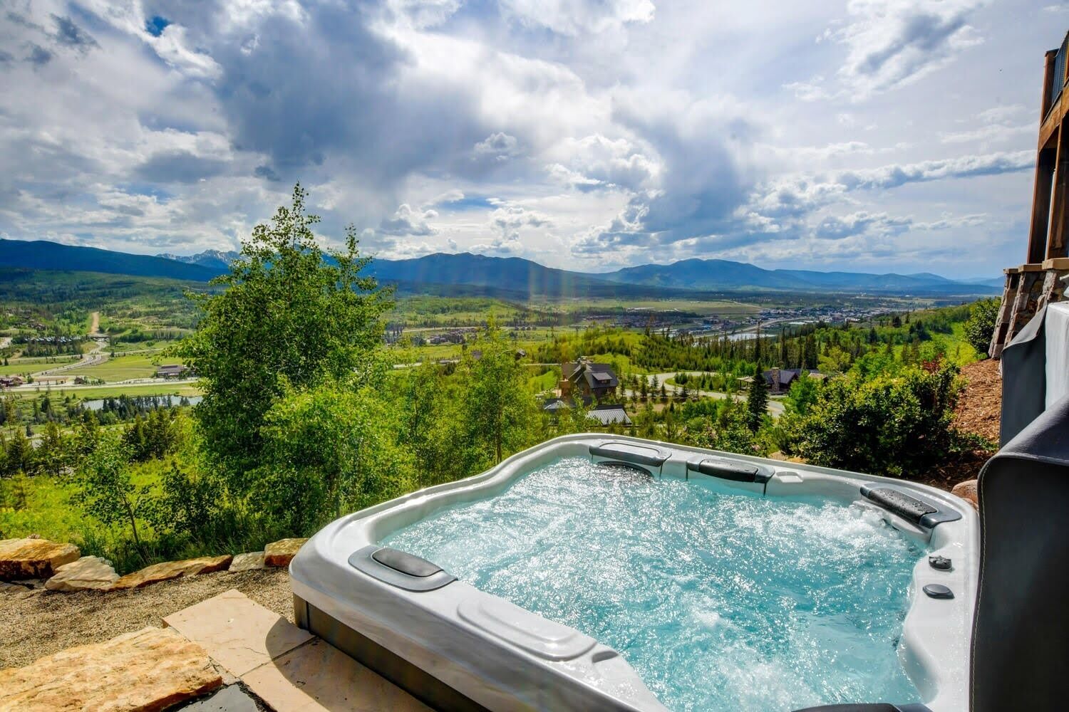 A hot tub with a scenic view of a valley and mountains.