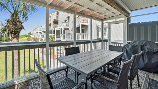 A covered outdoor patio with a table and chairs, overlooking a residential area with multiple buildings. - Dog Heaven · Pet-Friendly Beach·Pools & Pickleball (Port St. Joe)