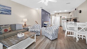 A modern living room with a sofa, two patterned chairs, a coffee table, and a dining area with white chairs and a table. - Dog Heaven · Pet-Friendly Beach·Pools & Pickleball (Port St. Joe)