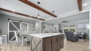 Una cocina amplia con una isla grande, vigas de madera e iluminación colgante.