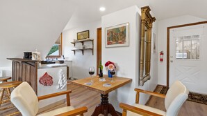 Un coin repas avec une table en bois, deux chaises, un bar avec des étagères et des œuvres d’art accrochées aux murs.