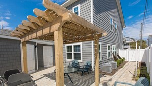 A covered patio with a wooden pergola, a barbecue grill, and outdoor seating. - Beach Music - North End VB (Virginia Beach)