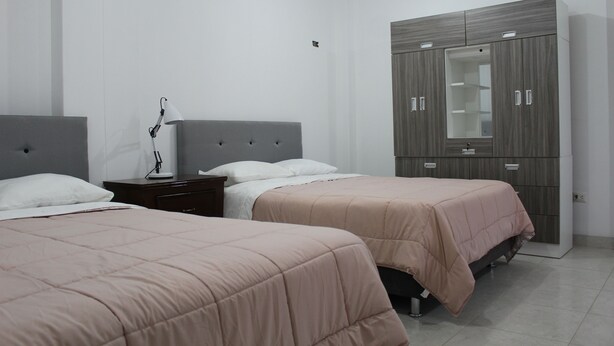 A hotel room with two beds, a wardrobe, a desk, and a lamp. - Hospedaje Las Parraz (Subtanjalla)