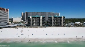 Ett hotell vid stranden med flera höga byggnader, en sandstrand och klarblå himmel.