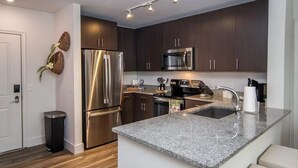 A modern kitchen with dark wood cabinets, stainless steel appliances, and a granite countertop. - Walk to the square and the grove! This 2BR 2BA is the perfect location.  (Oxford)