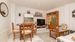 A living room with a dining table, chairs, a TV, and a wooden cabinet. - VEGALUZ - Cosy flat in the centre of Jerez with free Wifi (Jerez de la Frontera)