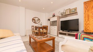 A modern living room with a glass-top coffee table, a TV, a dining area with chairs, and a sofa. - VEGALUZ - Cosy flat in the centre of Jerez with free Wifi (Jerez de la Frontera)