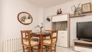 A dining area with a wooden table and chairs, a mirror, a cabinet, and a television. - VEGALUZ - Cosy flat in the centre of Jerez with free Wifi (Jerez de la Frontera)