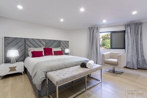 Restful retreat with a large bed, bench, and chair, set against a clean, minimalist backdrop.