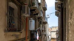 Une rue étroite bordée de vieux bâtiments, d’unités de climatisation et de quelques balcons.