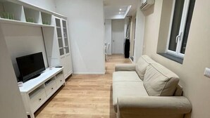 Un salon moderne doté d’un téléviseur à écran plat, d’un canapé et d’un plancher en bois.