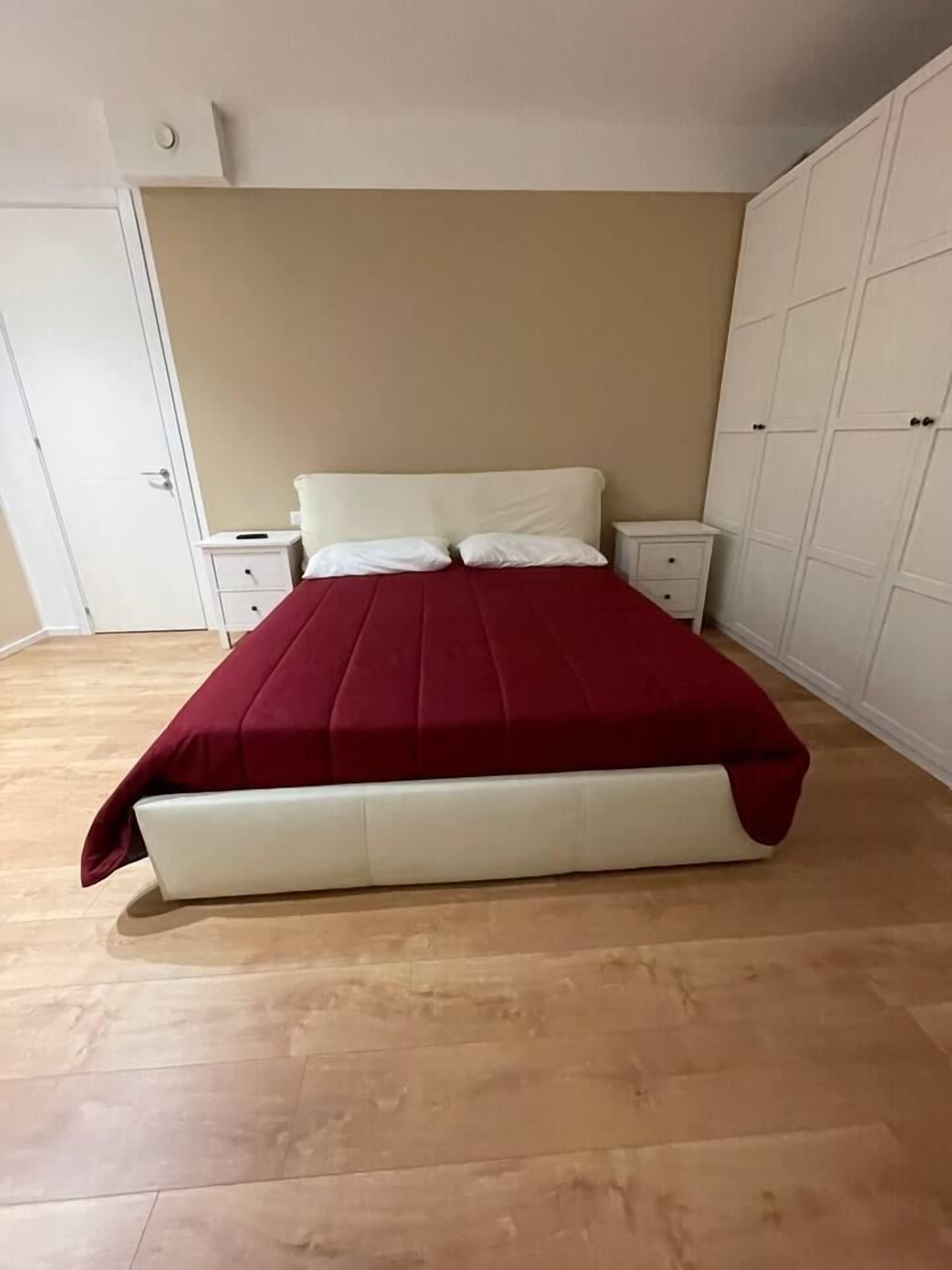 A bedroom with a bed, nightstands, and a wardrobe.